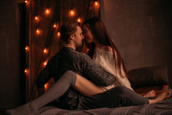 Love story фотосессия, в студии, девушка и парень целуются сидя на кровати