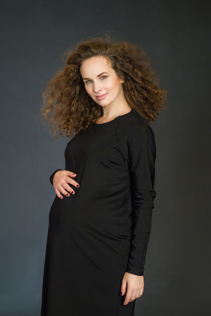 Фотосессия беременных в студии, фотограф Постникова Алиса, модель Анастасия Войцеховская сидящая на коленях на черном фоне